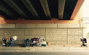 clothing and shopping cart under an overpass