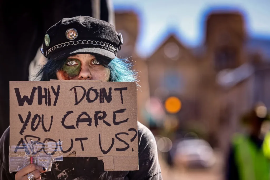 A student from the New Mexico School for the Arts holds a sign reading “Why Don’t You Care About Us?” during a walkout and protest against Project Jupiter, data centers and artificial intelligence at the Santa Fe Plaza on Tuesday, Oct. 27, 2026.